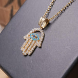 Pingente mão de fátima em ouro amarelo com safiras brancas e azuis.