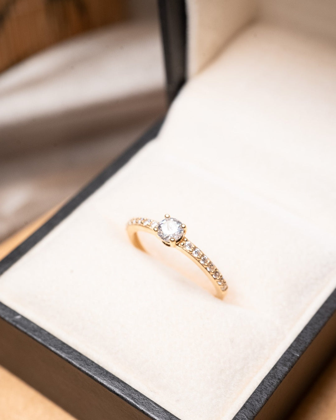 Anel solitário em ouro amarelo com safira central de 0.5ct e 10 safiras brancas laterais de 0.01ct cada.