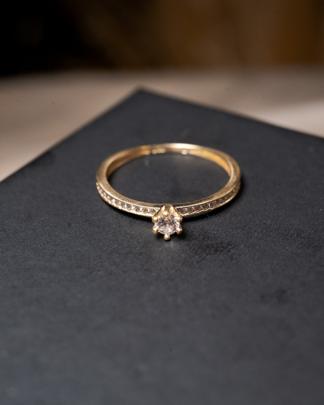 Anel solitário em ouro amarelo com safira central de 10 pontos e safiras laterais de 01 ponto. Peso 1.3g. Aro 16.