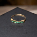 Meia aliança de ouro amarelo com 7 esmeraldas de 0.5 pontos cada. Peso 0.6g. Aro 13.