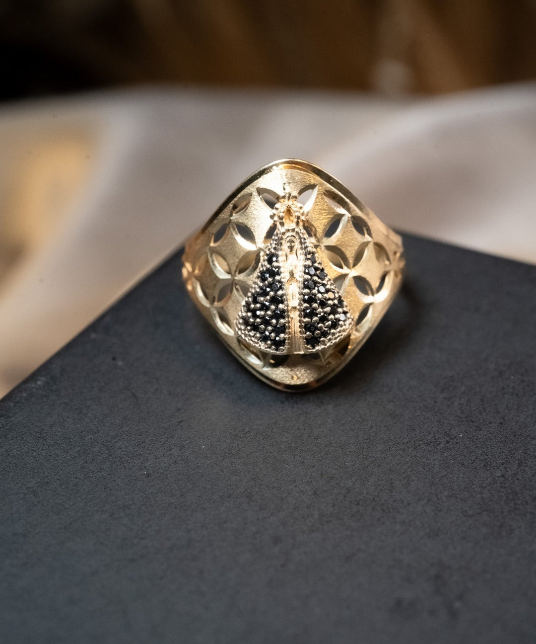 Anel em ouro amarelo com imagem de Nossa Senhora Aparecida e safiras azuis. Aro 21. Peso 3.1g.