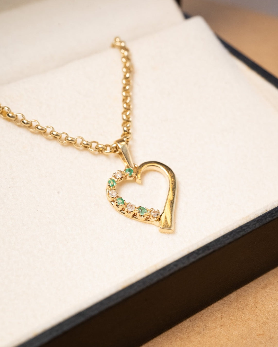 Pingente coração de ouro amarelo com diamantes e esmeraldas. Mede 2.4cm por 1.6cm e pesa 1.8g.