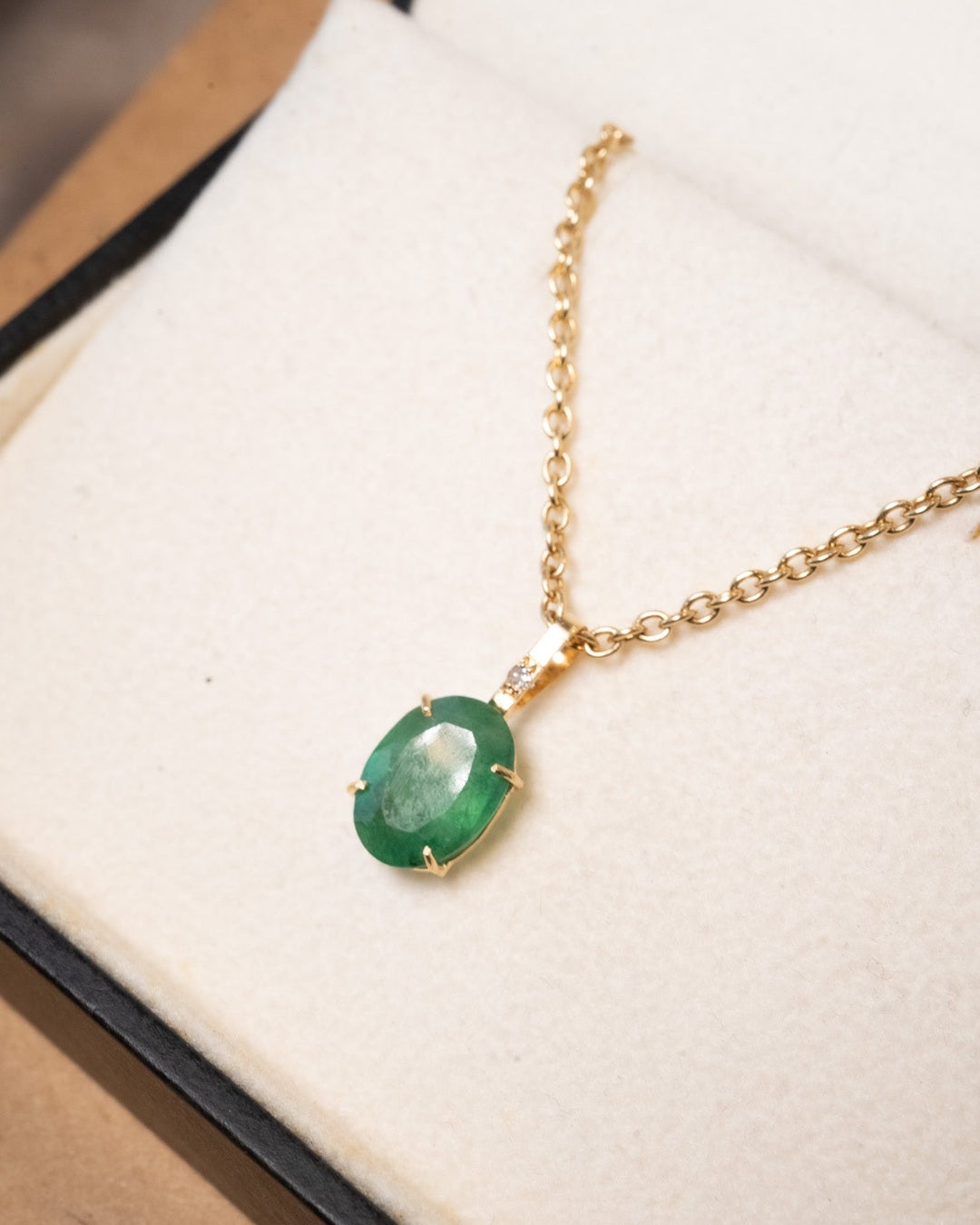 Pingente de ouro amarelo com diamante e esmeralda oval de 1.1x0.8cm. Altura 1.8cm e largura 0.8cm. Peso 0.8g.