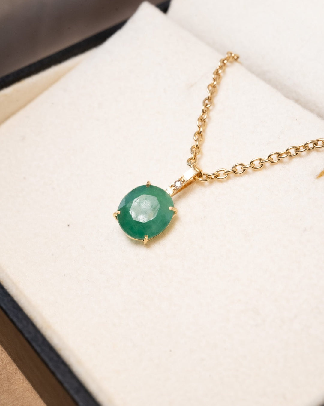 Pingente de ouro amarelo com esmeralda de 0.9x0.8cm e diamante. Medidas 1.7cm altura x 0.8cm largura. Peso 0.7g.