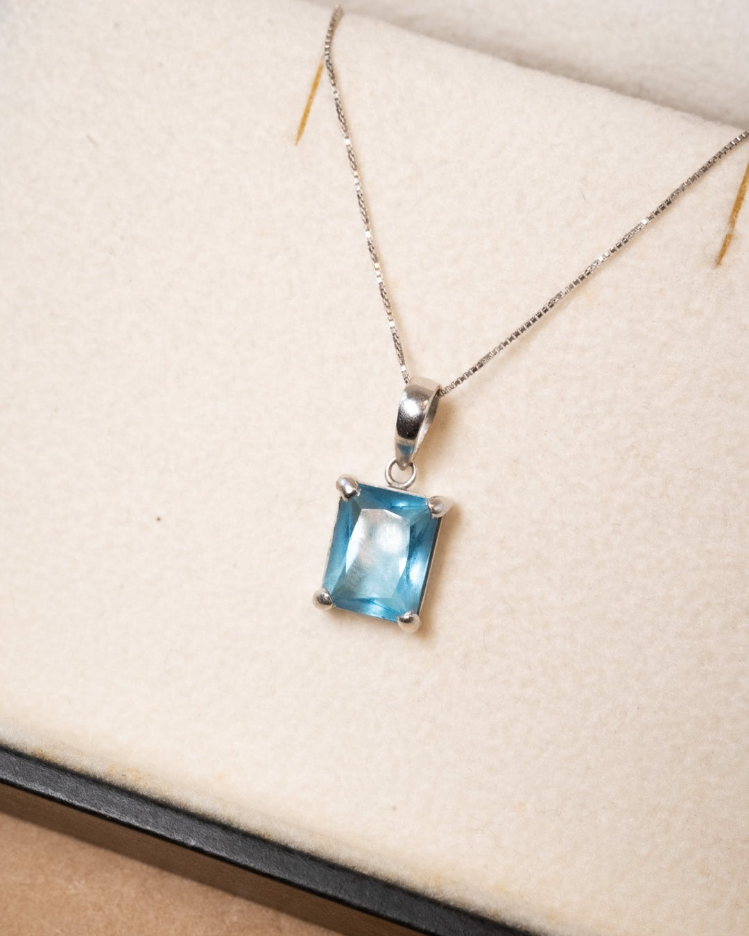 Pingente de ouro branco com topazio azul medindo 0.9 x 0.7cm e peso de 1.4g.