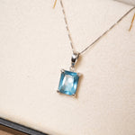 Pingente de ouro branco com topazio azul medindo 0.9 x 0.7cm e peso de 1.4g.