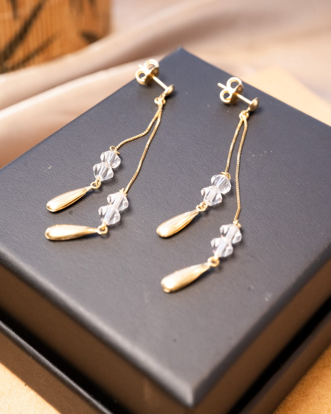 Brincos pendentes de ouro amarelo com cristais transparentes. Medem 6.0cm de altura e 0.4cm de largura. Peso 2.0g.