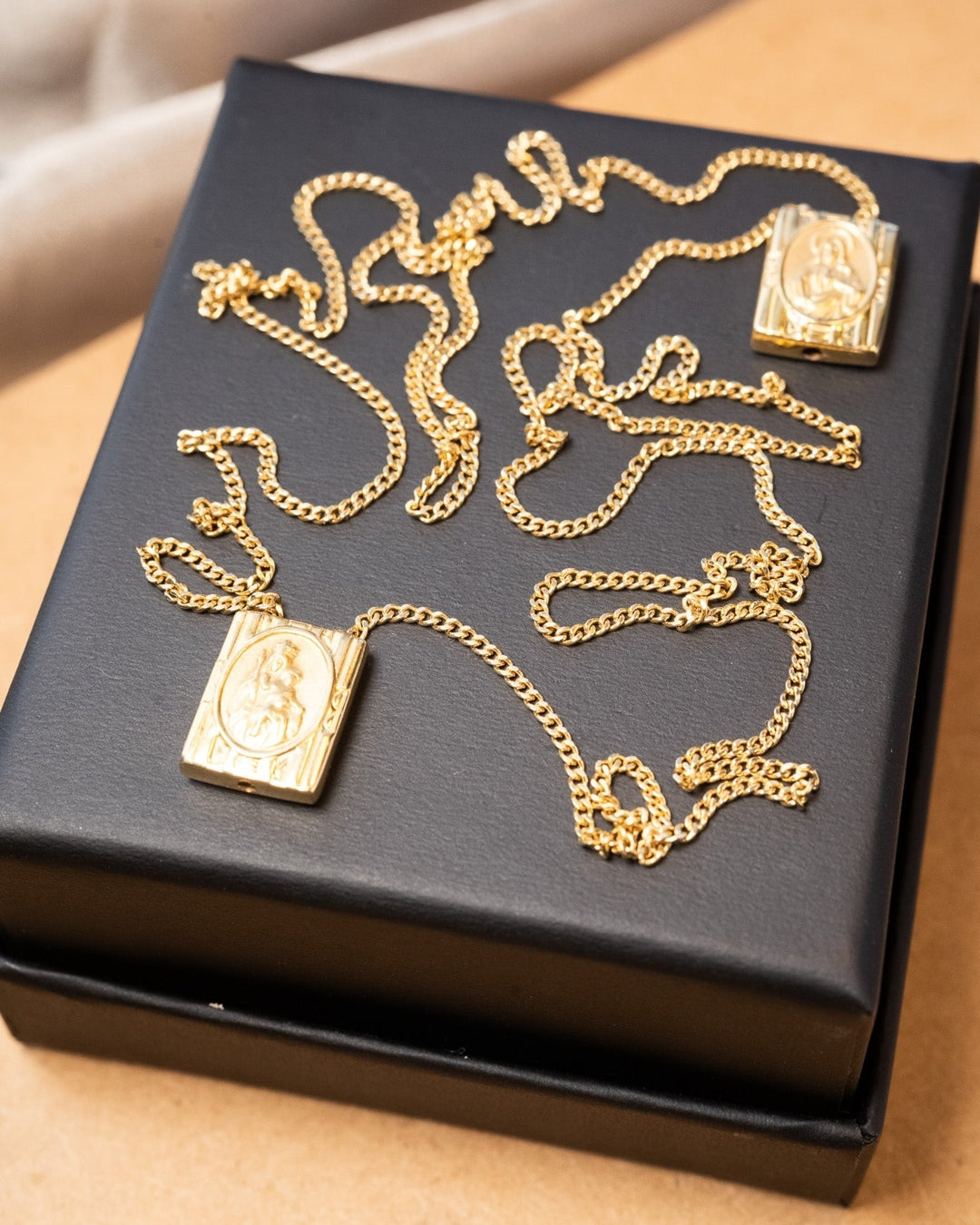 Escapulário de ouro amarelo com elos grumet e imagens do Sagrado Coração de Jesus e Nossa Senhora do Sagrado Coração.