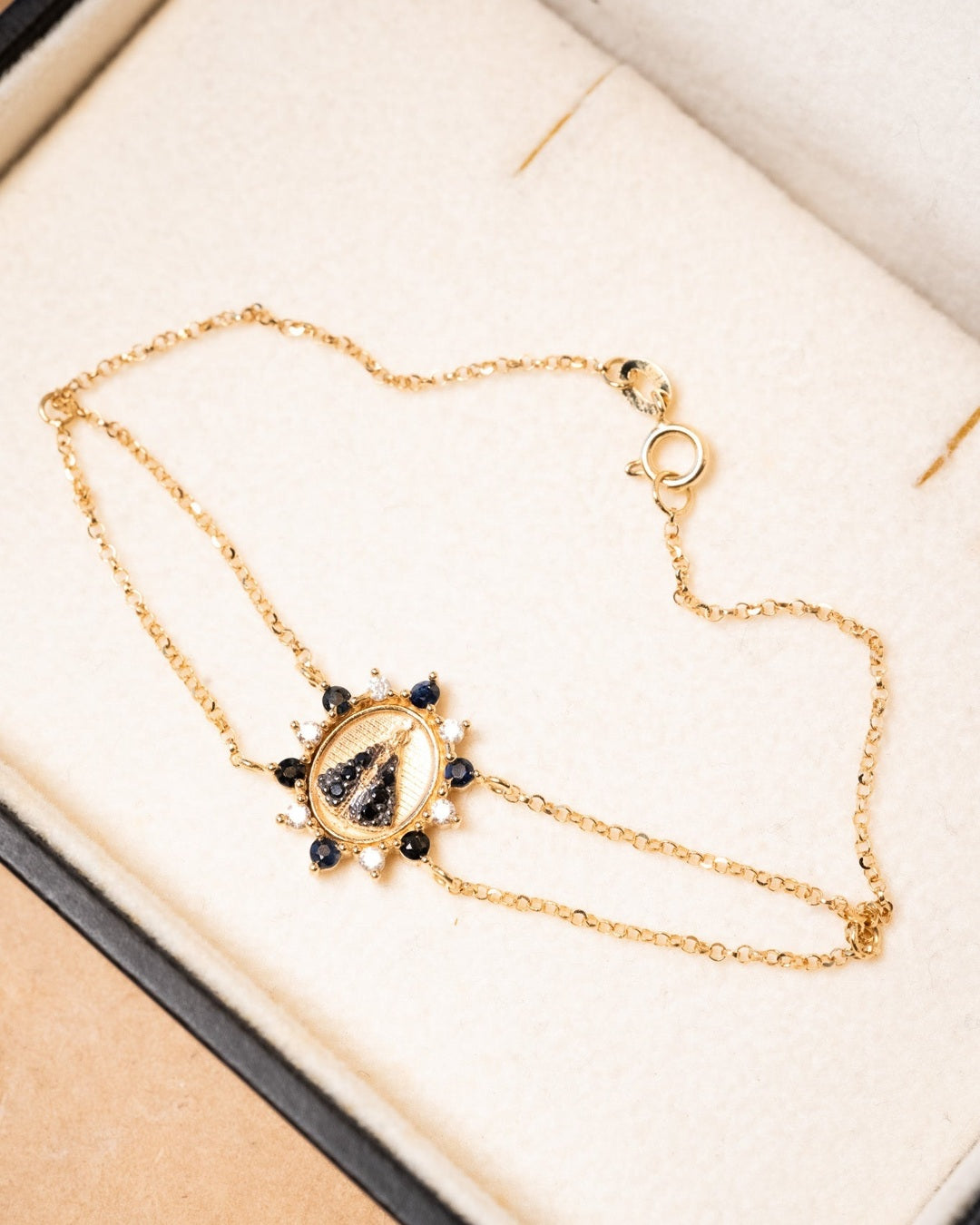 Pulseira de ouro amarelo com Nossa Senhora Aparecida cravejada de diamantes e safiras. 16cm de comprimento e 1.4cm de espessura.