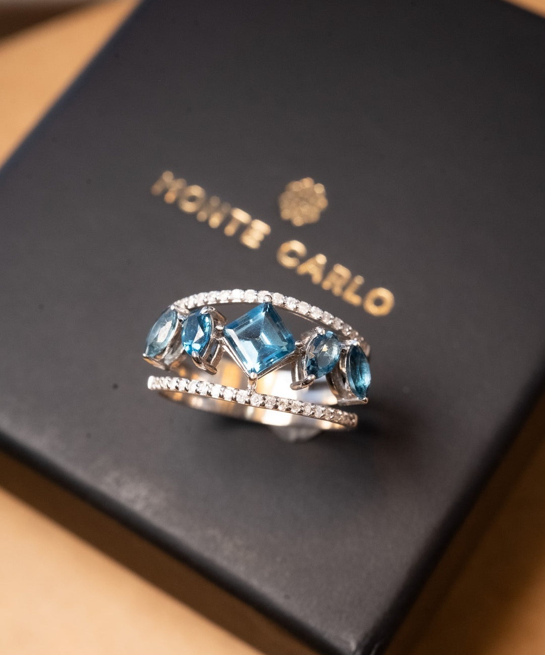 Anel Monte Carlo de ouro branco com diamantes e topázios azuis London. Aro 18 e peso 4.0g.