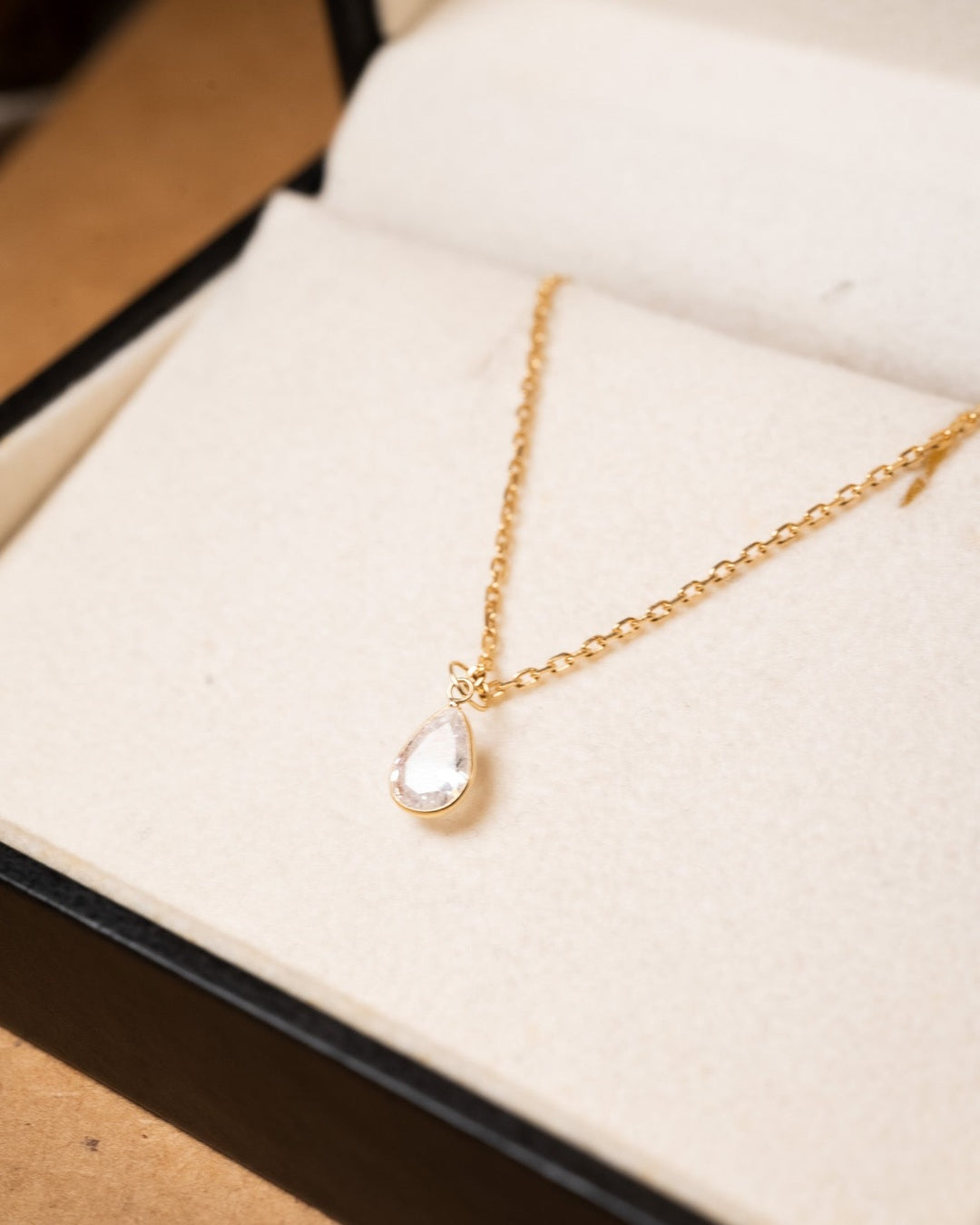 Pingente gota de safira branca em ouro amarelo. Mede 1.0cm x 0.5cm e pesa 0.2g.