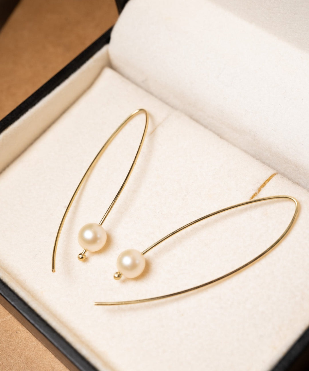 Brincos gancho de ouro amarelo com pérolas douradas de 0.7cm. Comprimento 5.0cm e peso 2.3g.