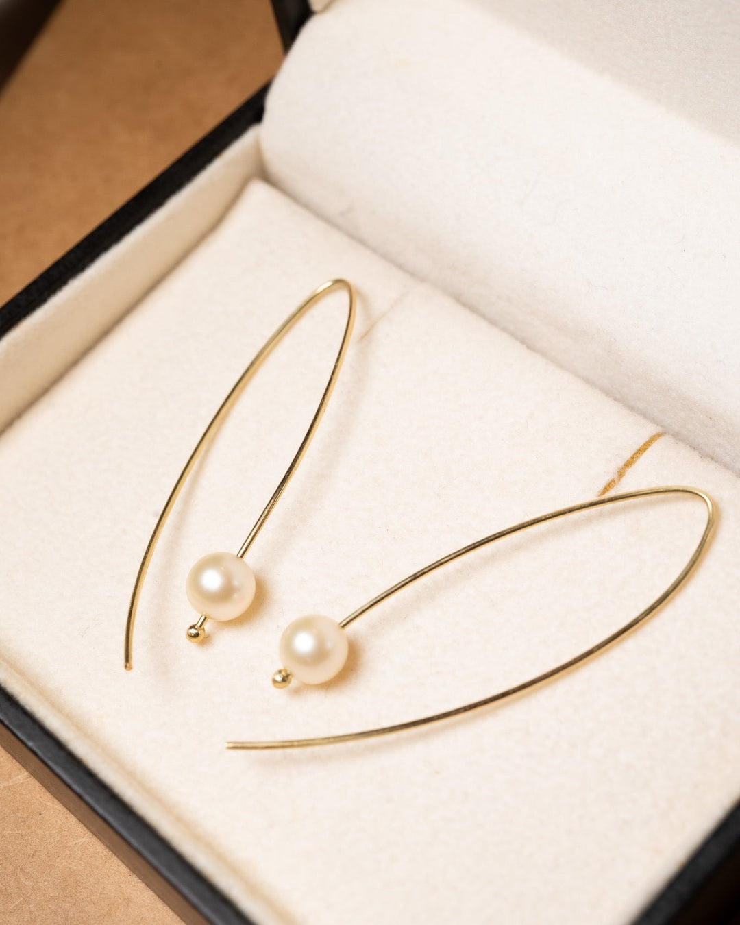 Brincos gancho de ouro amarelo com pérolas douradas de 0.7cm. Comprimento 5.0cm e peso 2.3g.