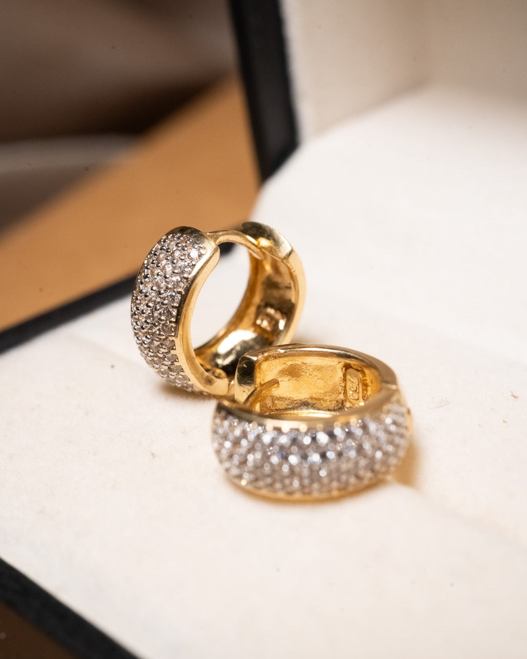 Brincos argolas em ouro amarelo com safiras brancas de 01 ponto. Peso 3.8g. Dimensões 1.3cm comprimento x 0.5cm largura.