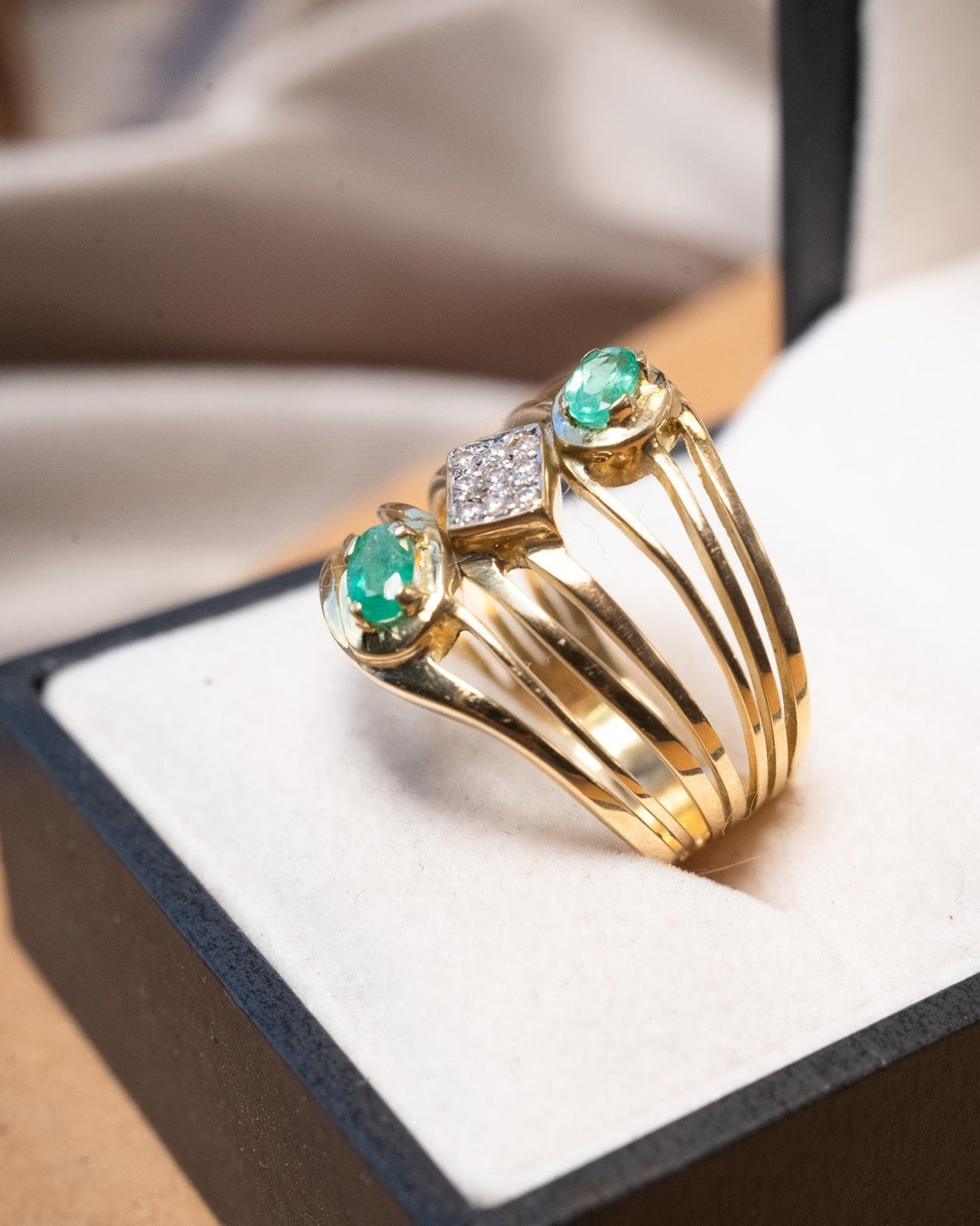 Anel bold em ouro amarelo com esmeraldas ovais de 0.3ct e safiras brancas de 0.02ct.