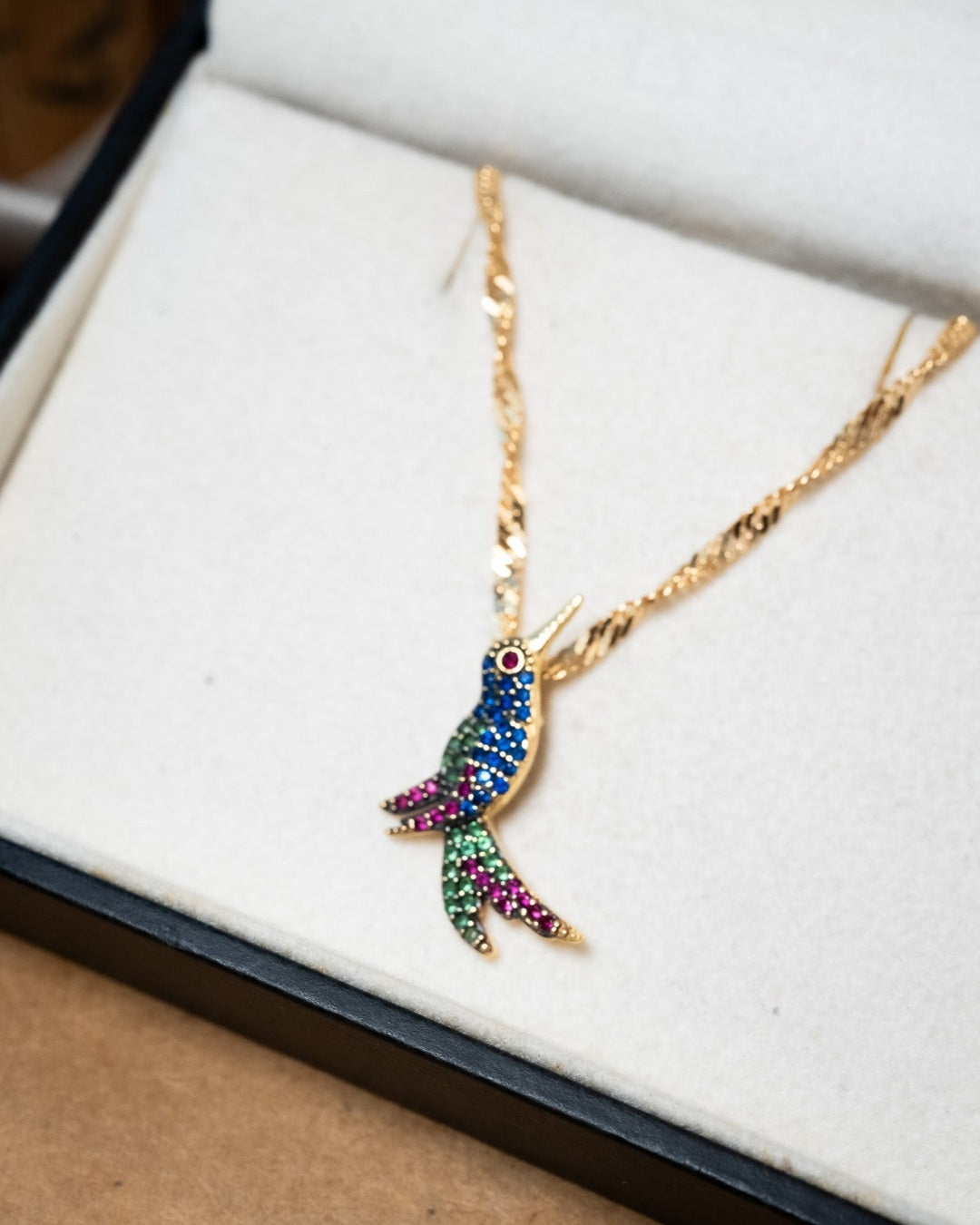 Pingente de beija flor em ouro amarelo com pedras brasileiras. Peso 1.6g. Dimensões 2.4cm de comprimento e 1.5cm de largura.