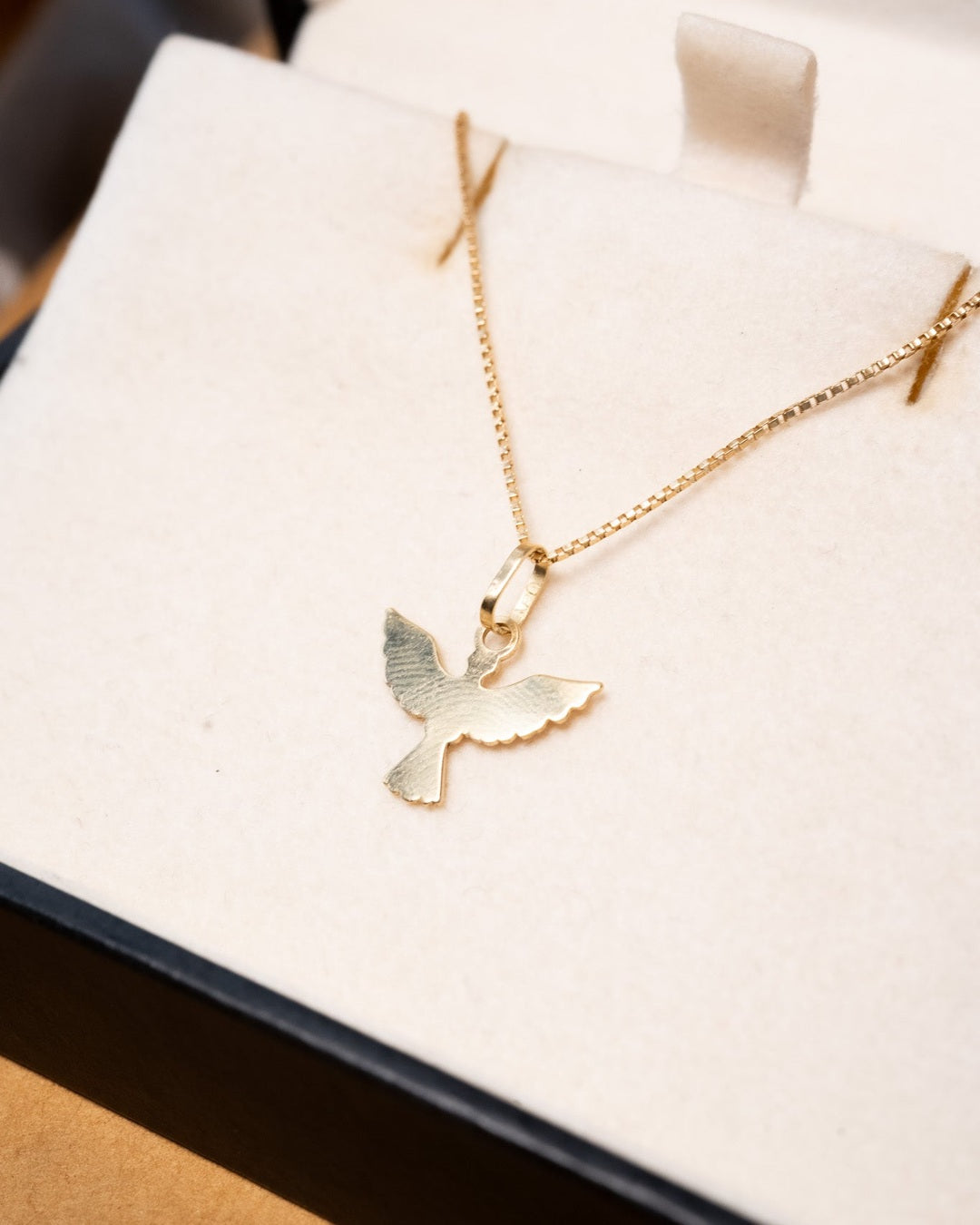 Pingente de divino espírito santo em ouro amarelo com peso de 0.6g e medidas de 1.5cm de comprimento e 1.0cm de largura.