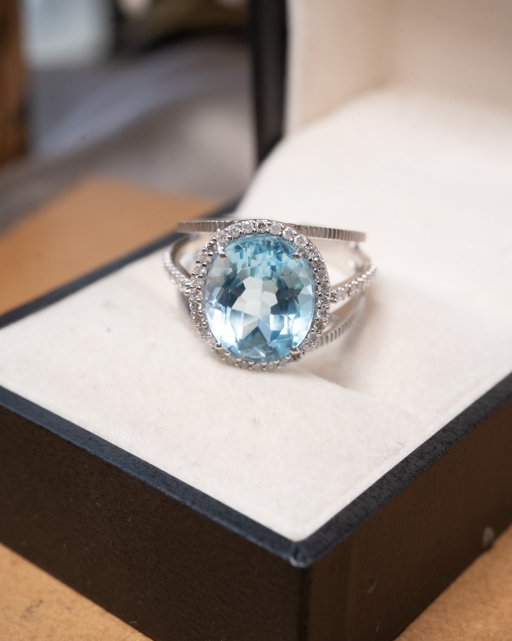 Anel em ouro branco com topázio azul oval de 1.2cm e diamantes brilhantes.