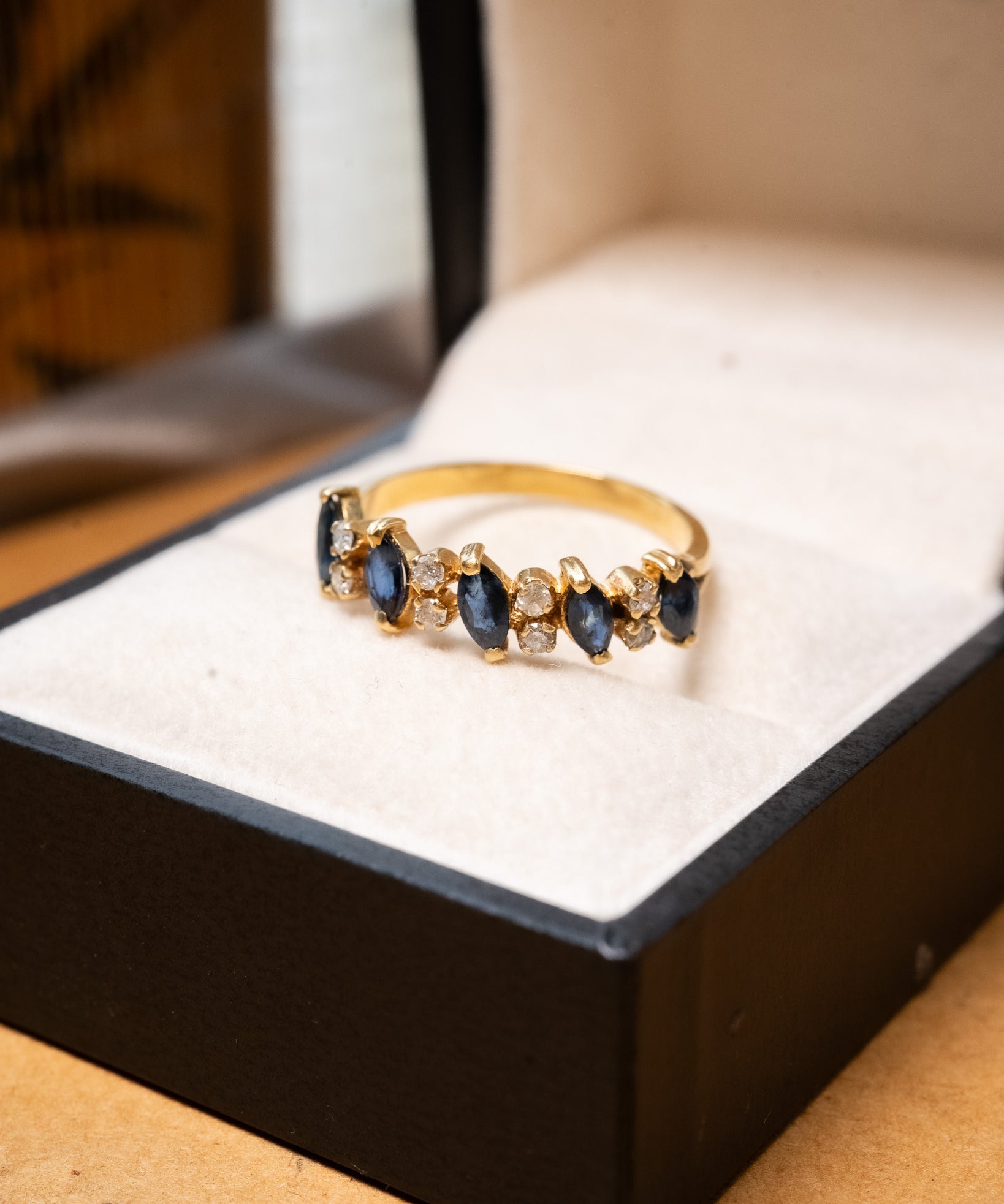 Anel meia aliança em ouro amarelo com safiras azuis e diamantes brancos.