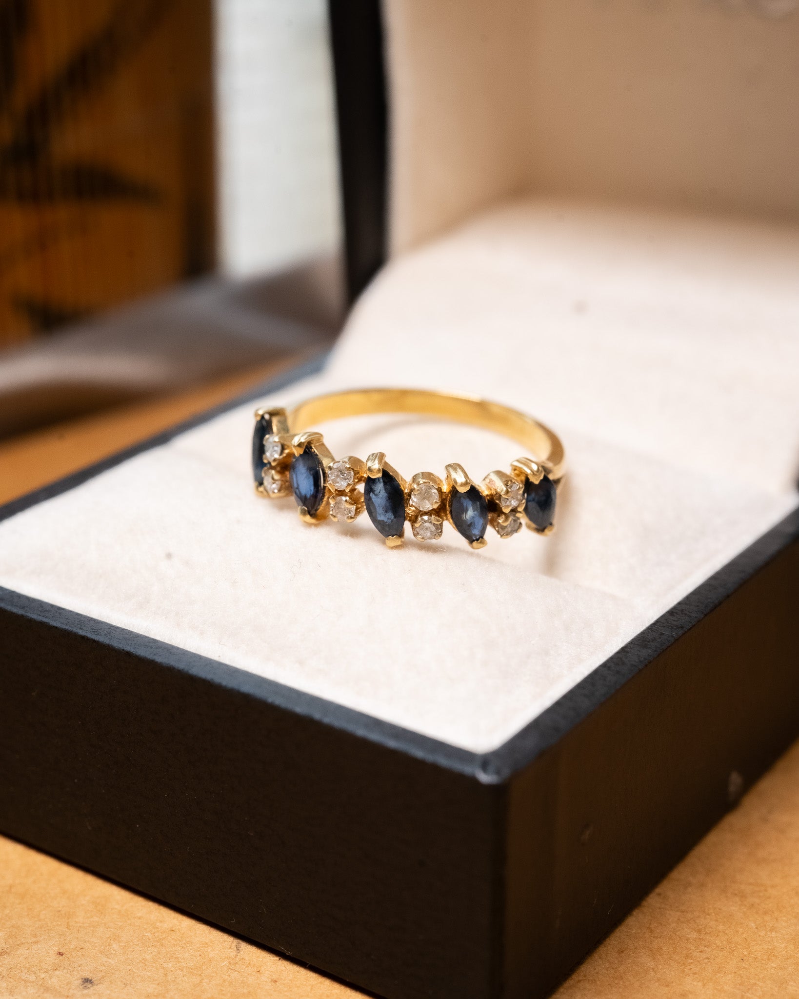 Anel meia aliança em ouro amarelo com safiras azuis e diamantes brancos.